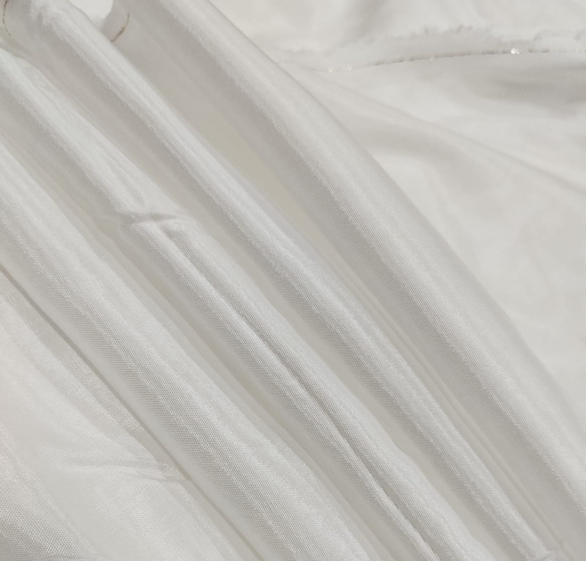 Soft white Audi fabric with a lightweight sheer texture and elegant shine ideal for dresses, sarees, dupattas, and designer garments.