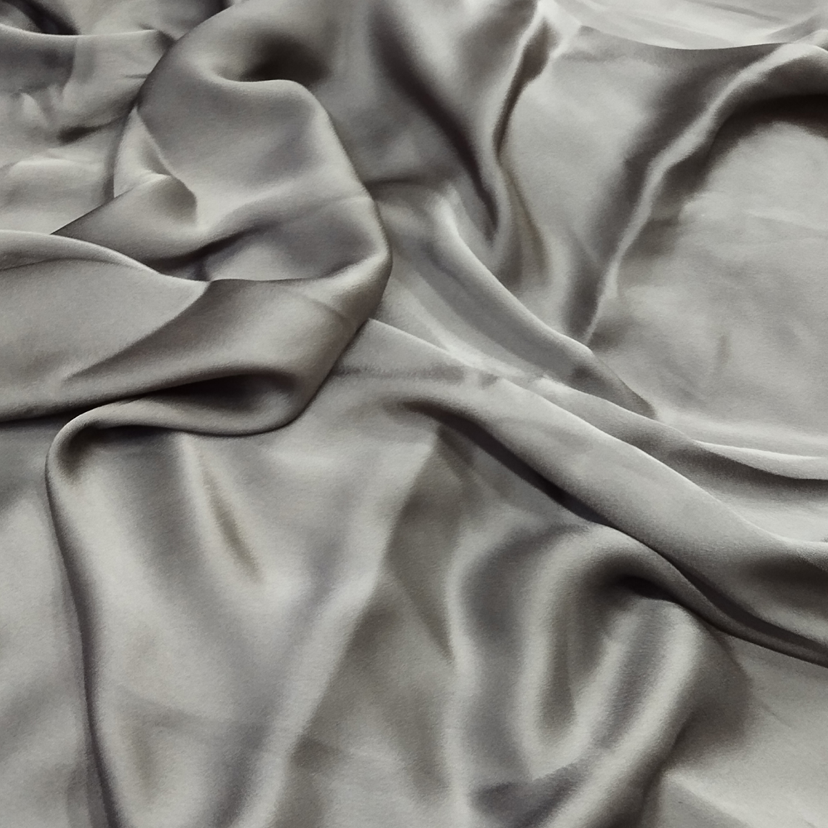 Silver grey satin fabric with a smooth silky texture, elegant sheen, and flowing drape