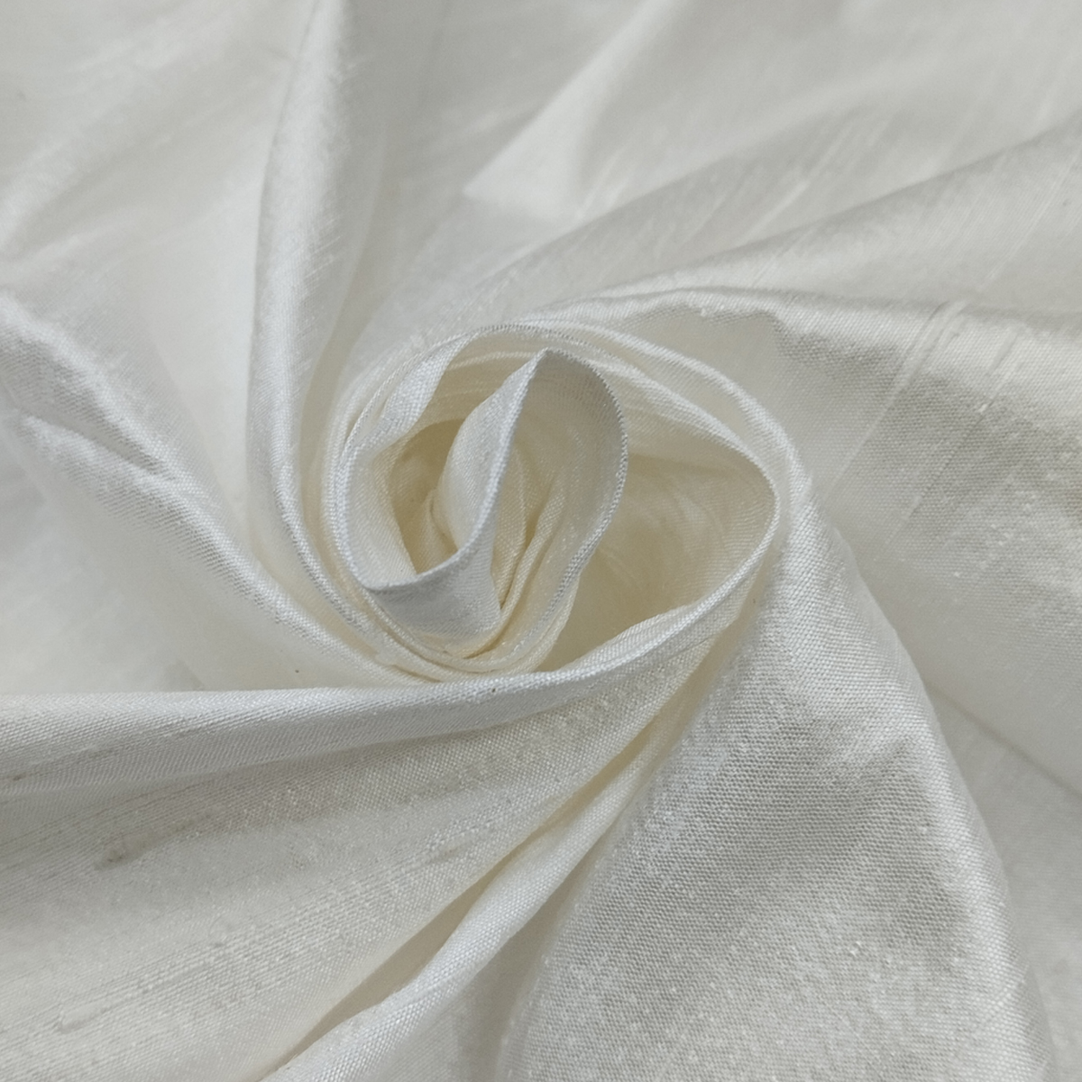 White 100 H Silk fabric with smooth glossy texture and elegant swirl drape pattern.