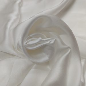 White heavy satin fabric with glossy silky texture and elegant drape arranged in swirl pattern
