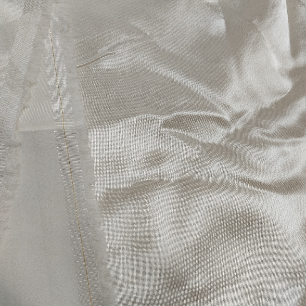 Premium cream Mashru silk fabric with smooth glossy texture and elegant drape pattern.
