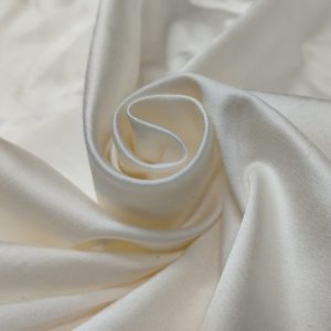 Premium Satin Lycra fabric with glossy smooth texture and stretch finish for gowns and designer wear.
