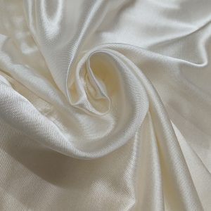 Premium cream Mashru silk fabric with smooth glossy texture and elegant drape pattern.