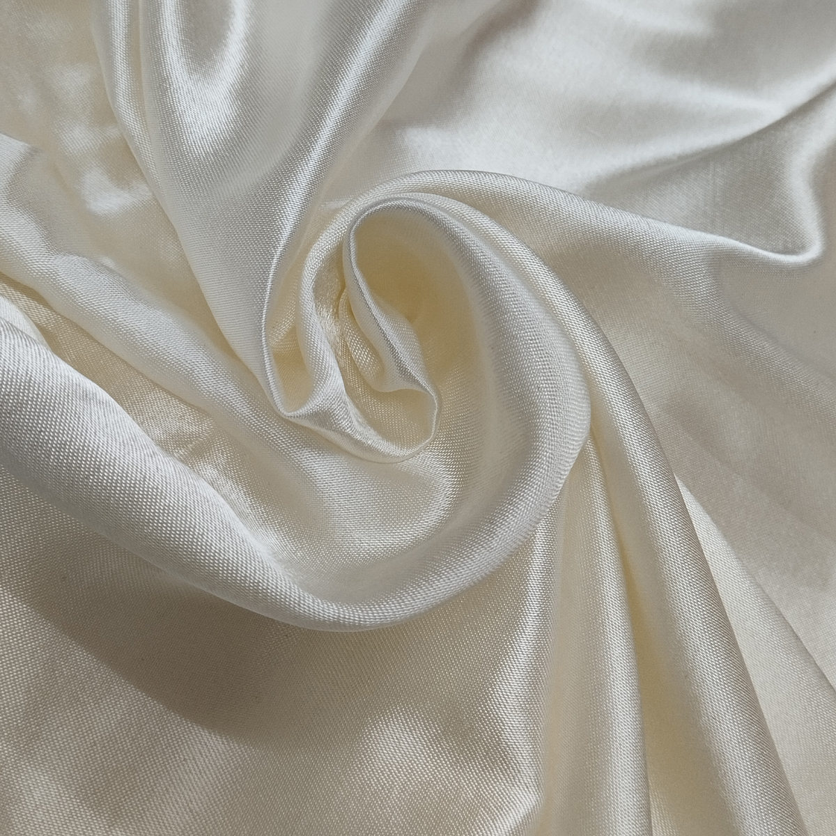 Premium cream Mashru silk fabric with smooth glossy texture and elegant drape pattern.