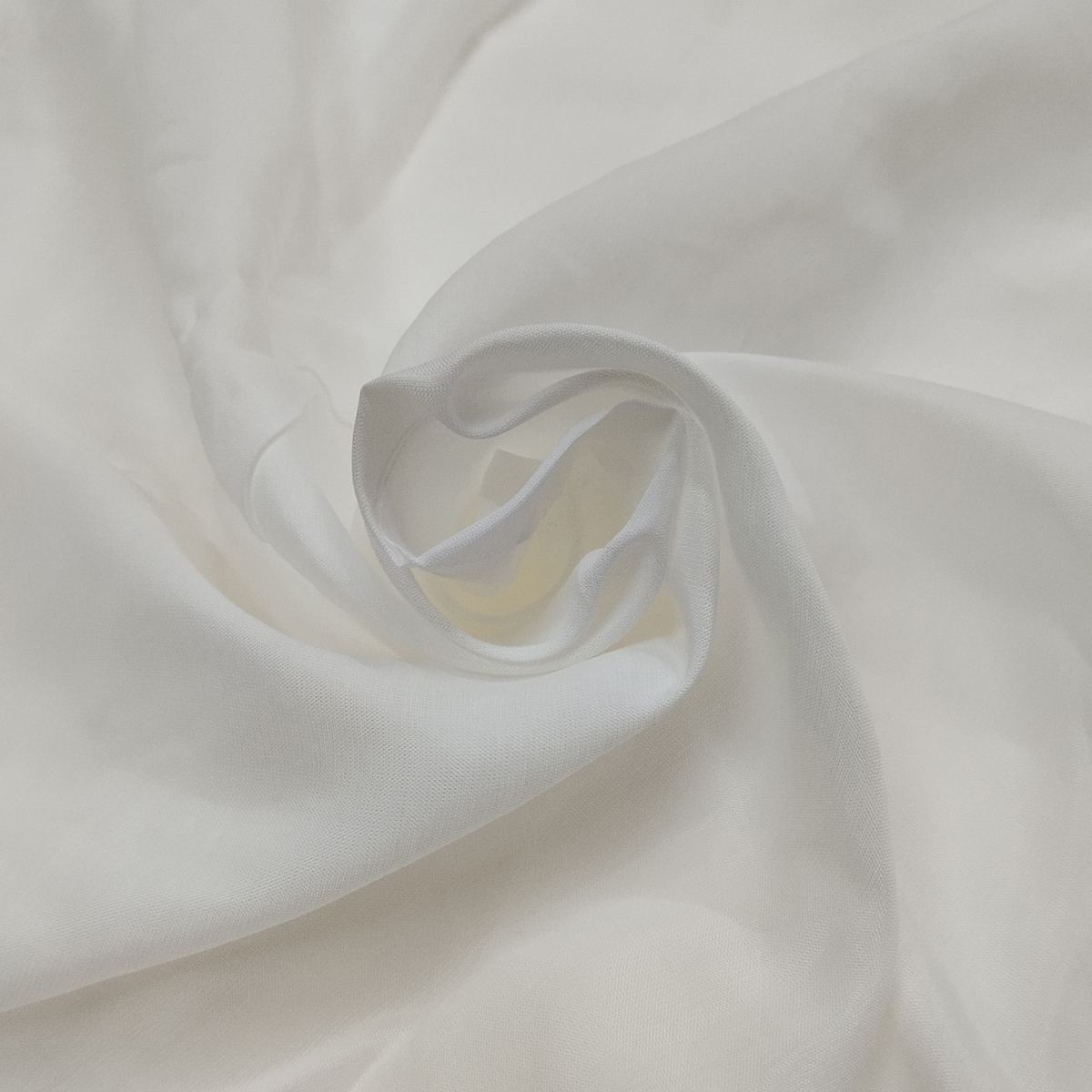 Soft white muslin dull fabric with lightweight texture and matte finish displayed in elegant folds.