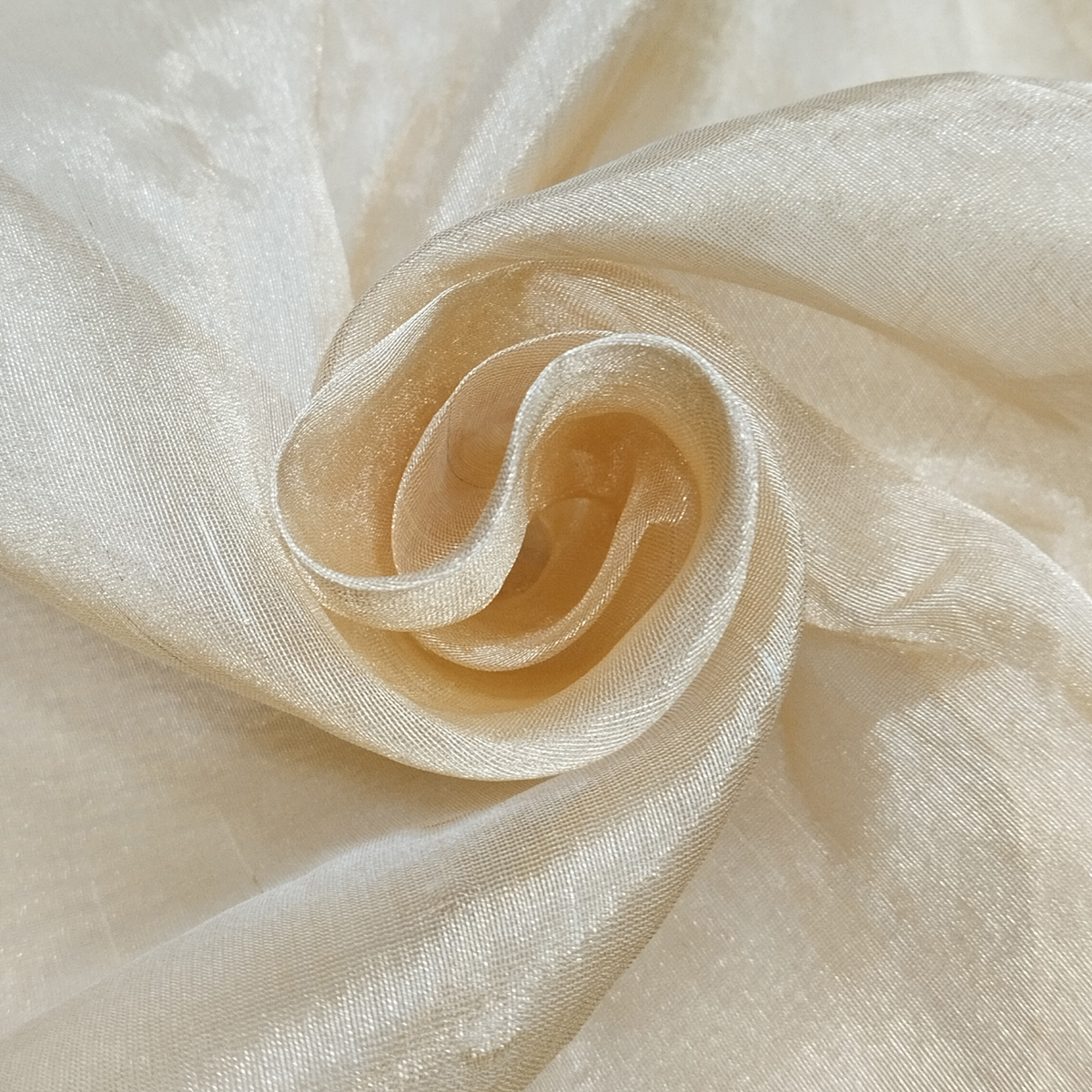 Soft pure tissue gold fabric with shiny texture and elegant drape arranged in swirl pattern.