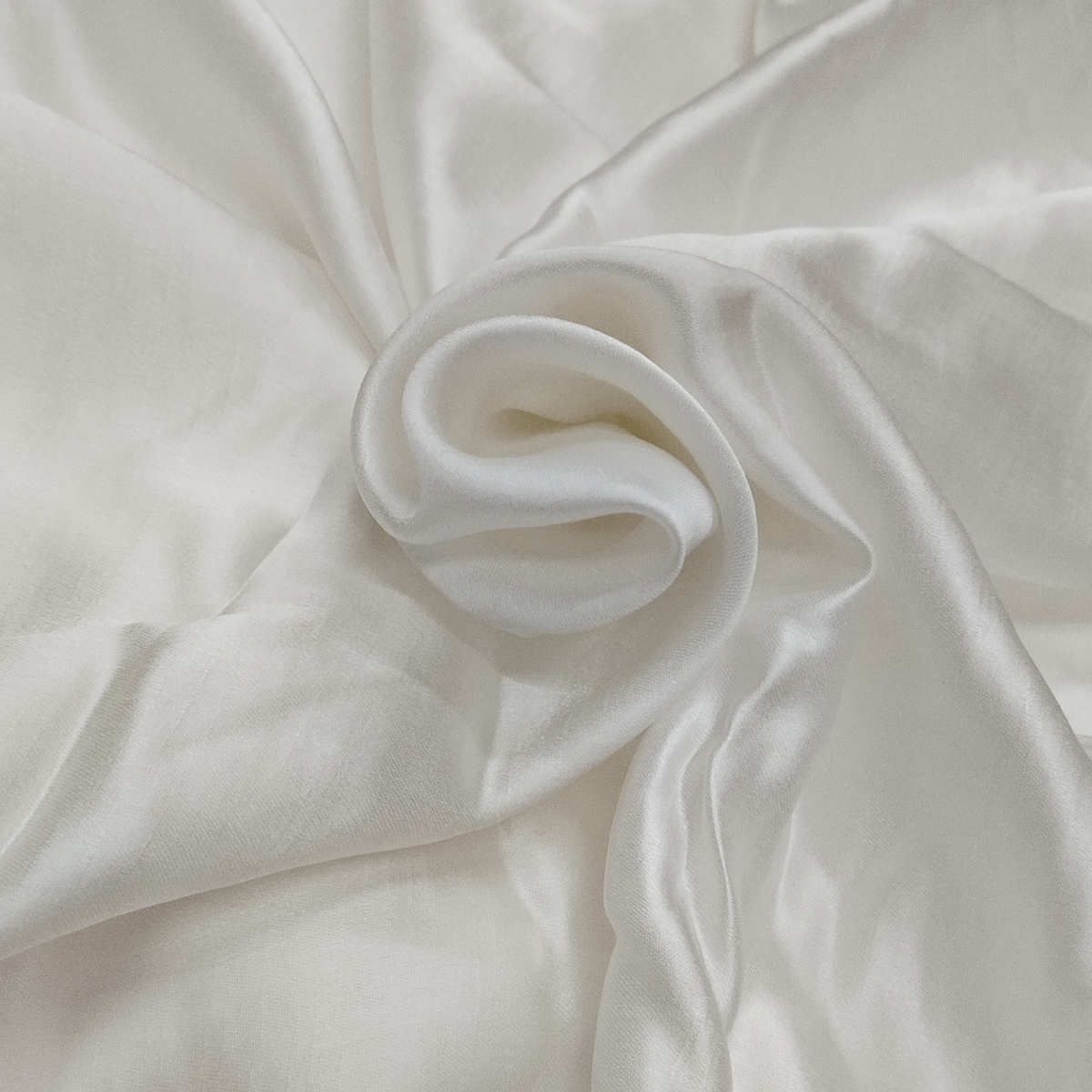 Premium white raw silk satin fabric with smooth glossy texture and luxurious flowing drape.