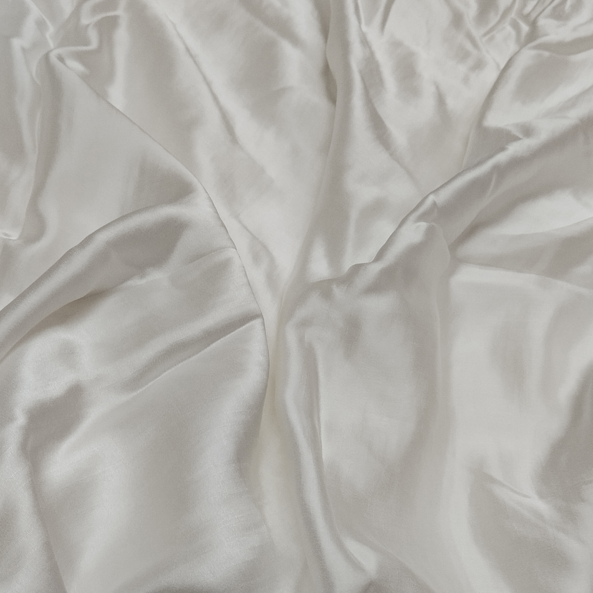 Premium white raw silk satin fabric with smooth glossy texture and luxurious flowing drape